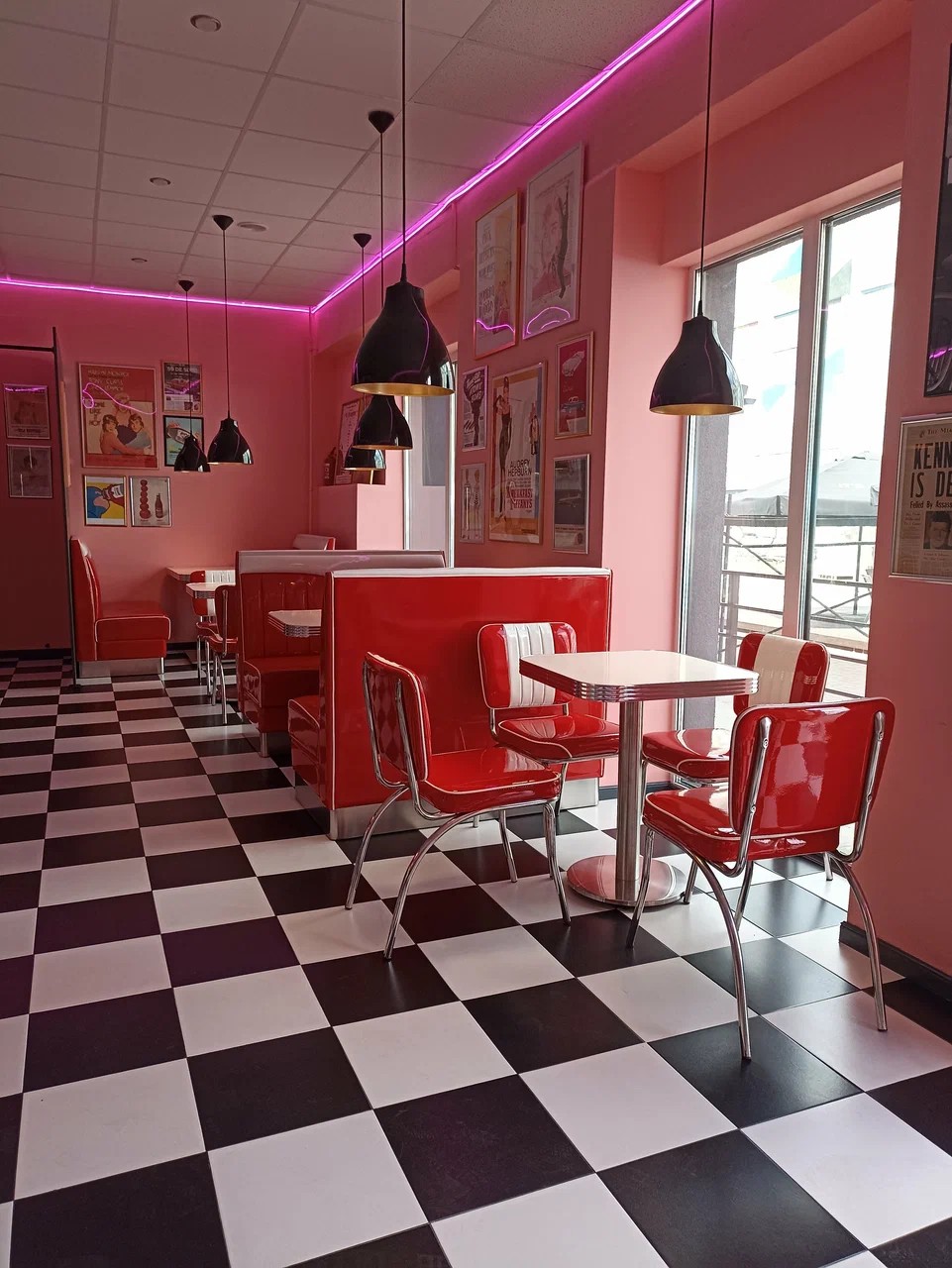 Glossy red leather booths and chrome chairs in a pink room with retro movie posters